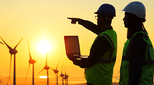 Windmills at sunset, two people with laptop