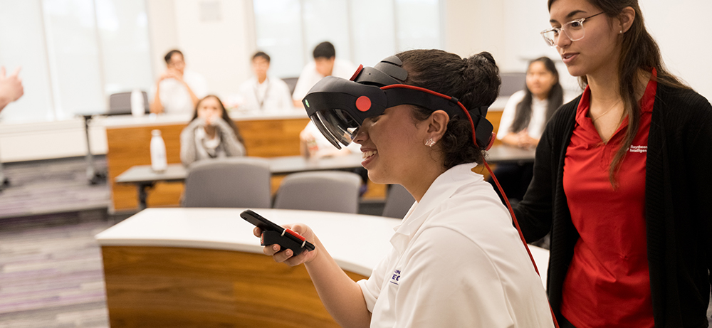In a Neeley classroom, a student wears googles while holding a phone.