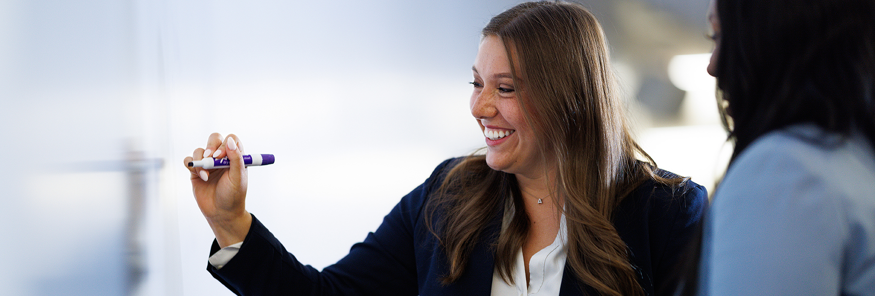 Section Image: Female student writing on a whiteboard 