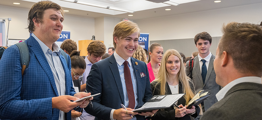 Section Image: Students at a career fair confer with a potential employer. 