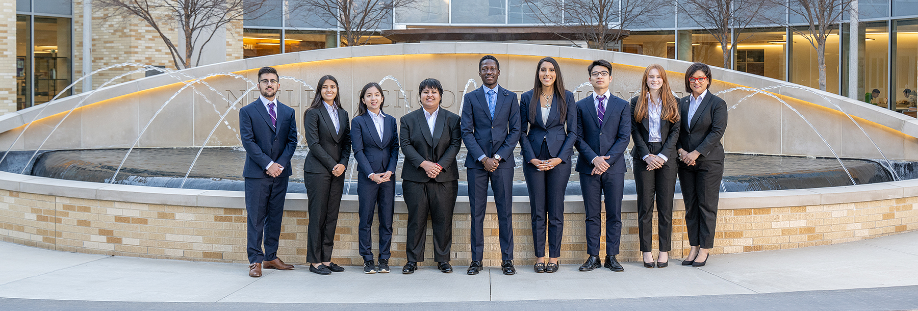 Section Image: Students in suits pose by the Neeley fountain 
