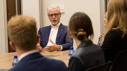 Speaker with students at a conference table