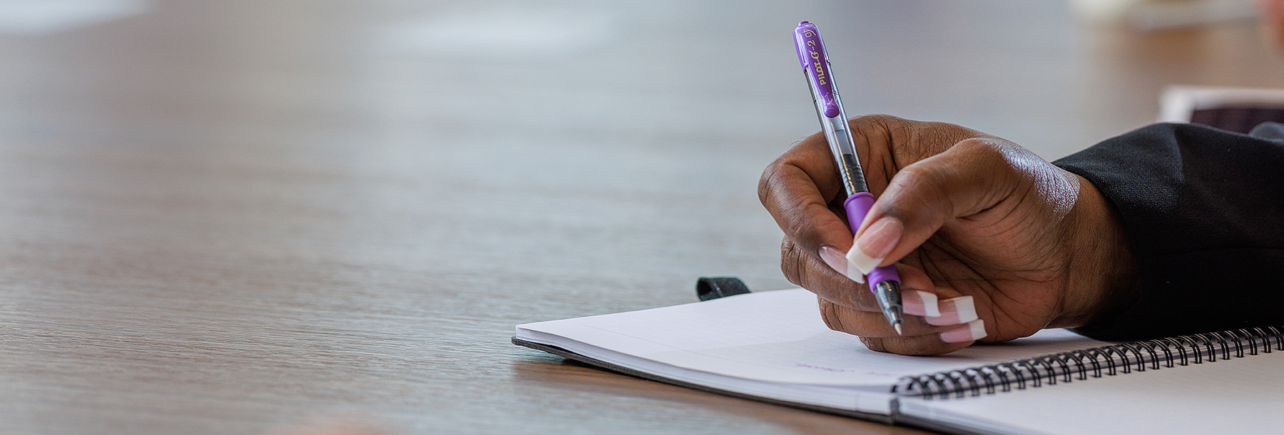 Section Image: Hand with pen poised over notebook 