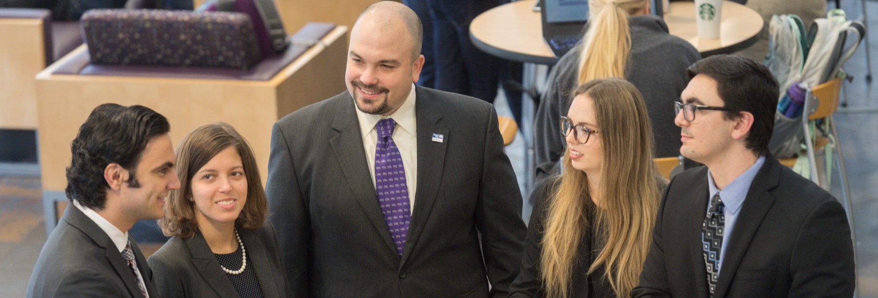 Section Image: People in suits talking in the Smith atrium 
