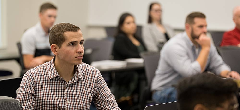 Wind turbines in the distance with 2 workers pointing to them at sunset 
