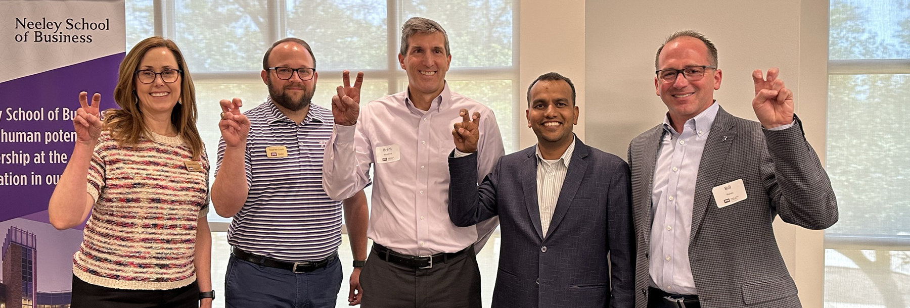 Section Image: TCU Accounting faculty and alumni with their "frogs up" 