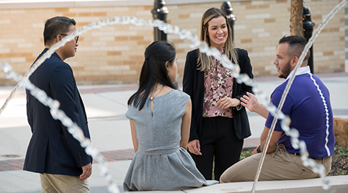 Section Image: Four MBA students with their frogs up at the Neeley Fountain 