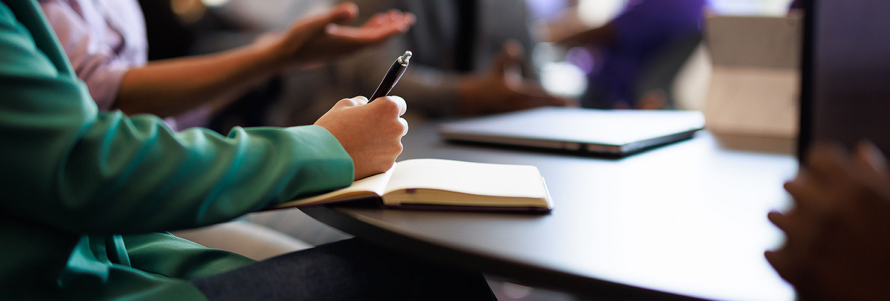 Section Image: Notepad on table and women with pen in hand 