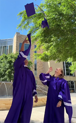 Brandi and Kyle tossing their caps in the air outside of Neeley