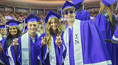 Graduates take pictures in cap and gown with family outside of Schollmaier Arena 